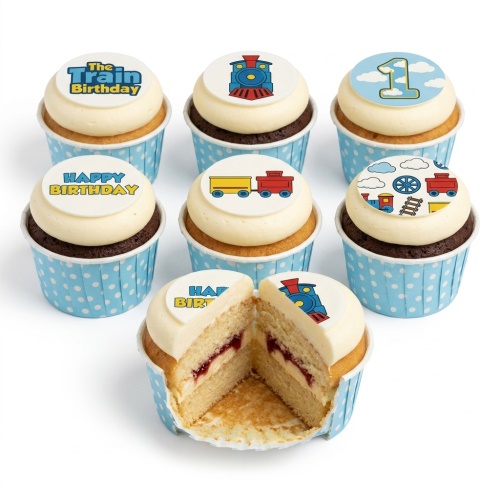 Assortment of train themed birthday cupcakes with blue polka dot wrappers, some with '1' and 'Happy Birthday' toppers.