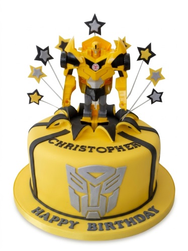 Yellow round cake with a Transformers Bumblebee figure, black and yellow star toppers, and black ribbon details.