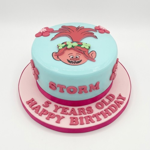 Round light blue Trolls Poppy birthday cake with pink flowers and a personalised message.