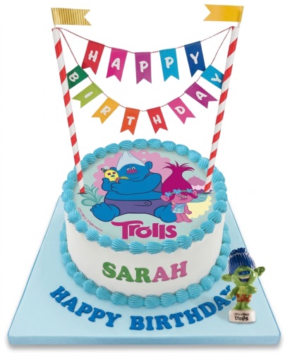 Round white Trolls birthday cake with blue piping, "Happy Birthday" banner, and Trolls characters.