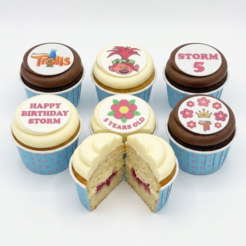 Selection of Trolls and floral themed birthday cupcakes with custom age and message toppers.