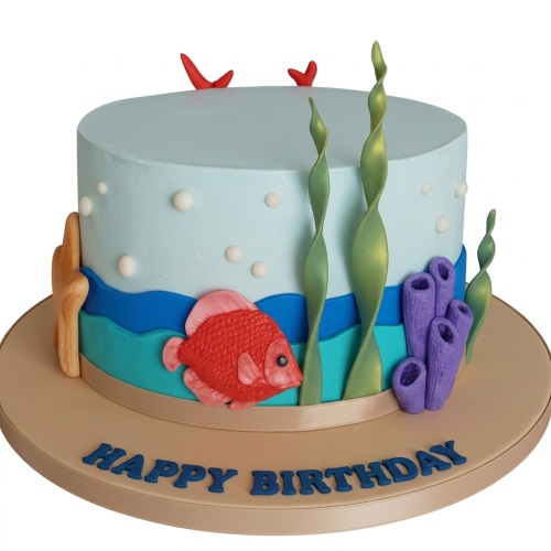 Round light blue birthday cake with red fish, green seaweed, purple coral, white bubbles, and a starfish on a beige board with "Happy Birthday".