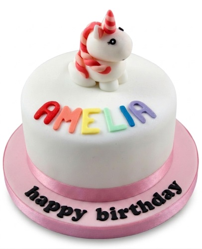 White round unicorn birthday cake with pink ribbon and personalised name.