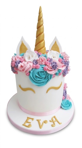 White unicorn cake with golden horn, ears, eyes, and pink, purple, white, teal buttercream flowers.