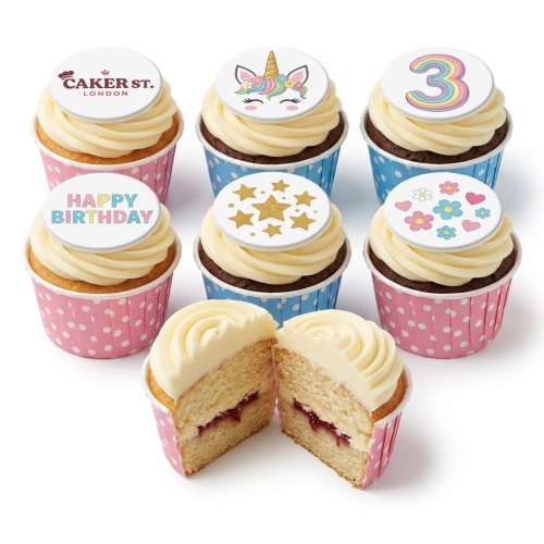 A set of birthday cupcakes with unicorn, gold stars, pastel flowers, and a rainbow number 3 topper, with one cupcake cut open showing jam filling.