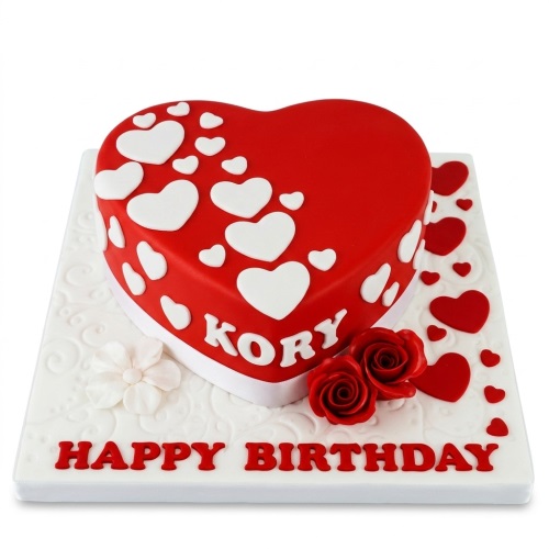 Red heart-shaped birthday cake decorated with white hearts, red sugar roses, and a personalised message.