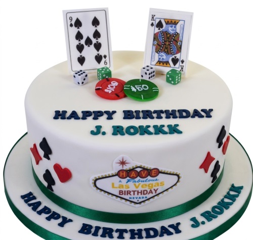 White round cake with Las Vegas casino theme, featuring playing cards, poker chips, dice, and a Las Vegas sign.