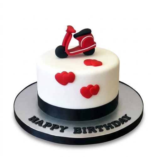 White round cake with a red scooter topper and red heart decorations, with a black ribbon base.