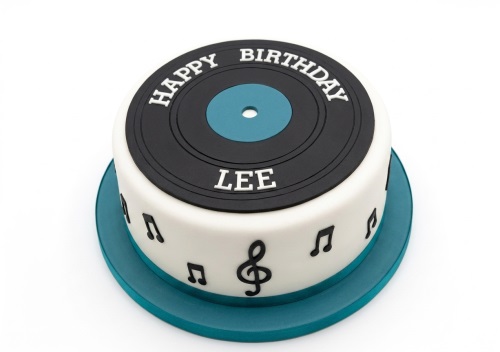 Round white birthday cake with a black vinyl record top and musical notes.