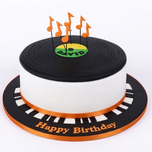 Round white cake with black vinyl record top, orange musical note toppers, and piano key base.