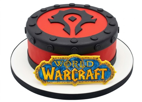 Round World of Warcraft themed birthday cake with red and black fondant, featuring the Horde symbol and game logo.