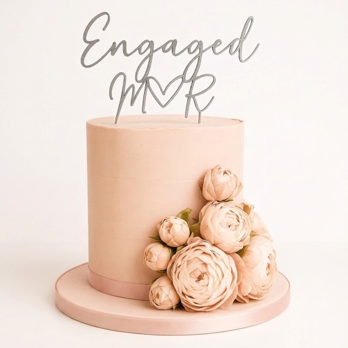 Elegant peach engagement cake with floral decorations and custom initials topper.