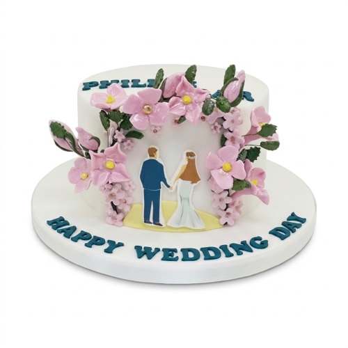 White wedding cake with pink floral arch, bride and groom figures, and "Happy Wedding Day" message.