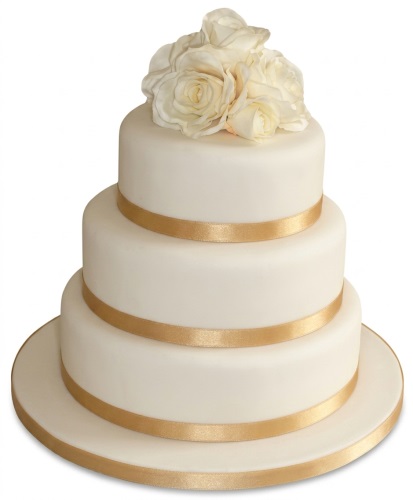 Three-tiered white wedding cake with gold ribbons and cream roses on top