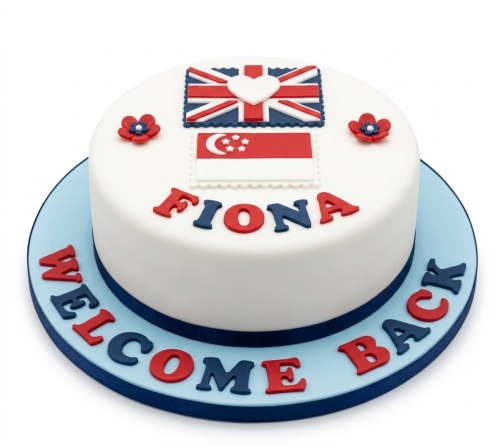Round white cake with Union Jack and Singapore flags, red and blue flowers, and a 'Welcome Back' message.