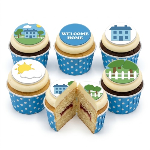 Six cupcakes with white frosting and blue polka dot wrappers, topped with edible discs featuring houses, trees, sun, and "WELCOME HOME" text. One cupcake is cut in half, showing a jam filling.