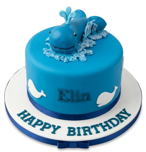 Blue round birthday cake with a whale topper, white whale silhouettes, and a custom message area.