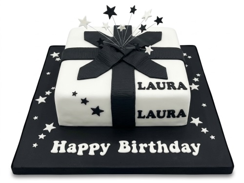 White square cake shaped like a gift box with a black ribbon and bow, decorated with black and white stars on a black cake board with 'Happy Birthday' message.