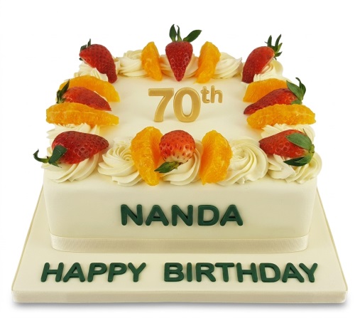 Rectangular fresh fruit birthday cake with cream swirls, strawberries, orange segments, and a gold custom age topper.
