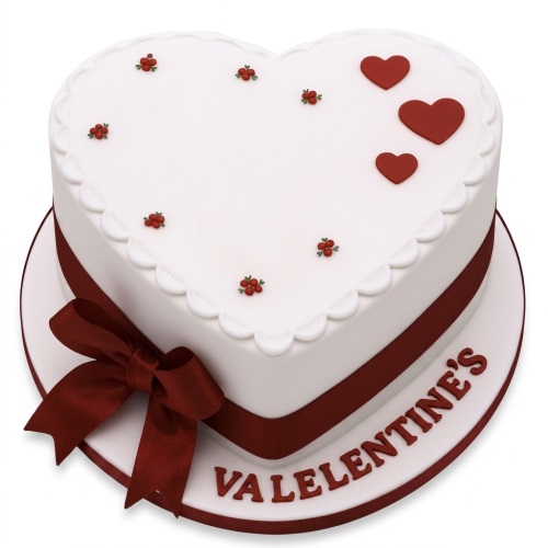 Heart-shaped white cake with red hearts, berry decorations, and a red ribbon.