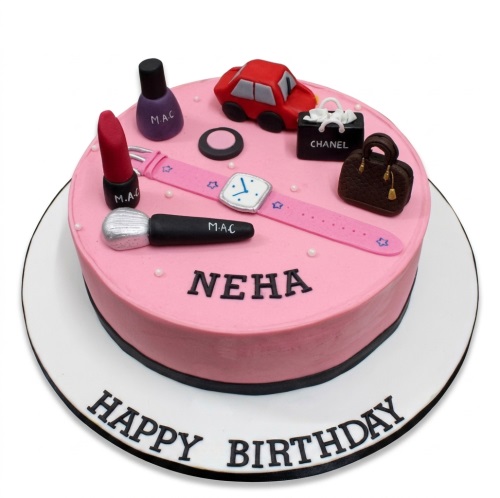 Pink birthday cake with fashion and beauty themed toppers including a car, handbag, makeup, and watch.