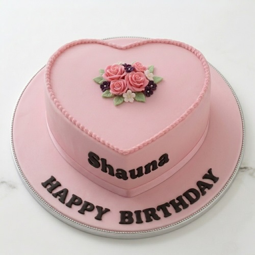 Pink heart-shaped birthday cake with sugar roses and personalised message.