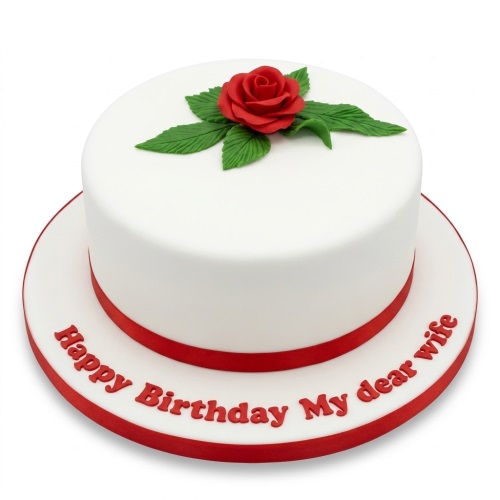 White round birthday cake with a red sugar rose, green leaves, and red ribbon.