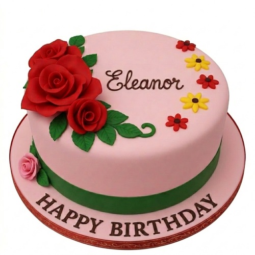 Elegant pink birthday cake adorned with red roses, green leaves, and small yellow and red flowers, with a green ribbon band.