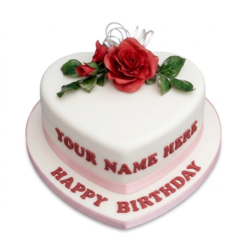 White heart shaped birthday cake with red sugar roses and green leaves, pink ribbon, and custom message.