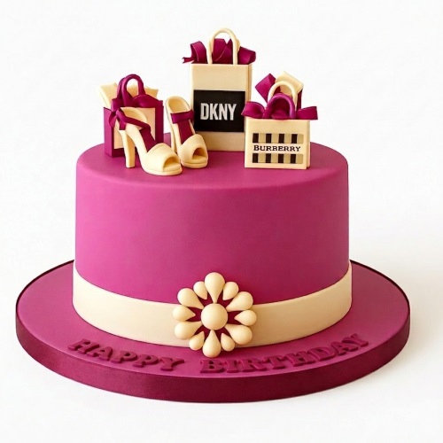 Round pink birthday cake with cream band, decorated with edible high heels and miniature designer shopping bags, with 'Happy Birthday' on the board.