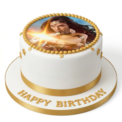 Round white birthday cake with Wonder Woman edible image, gold beads, stars, and 'Happy Birthday' message.