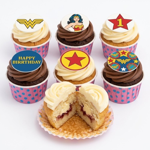 Set of Wonder Woman themed birthday cupcakes with various superhero toppers and pink polka dot cases, including one cut open to show jam filling.