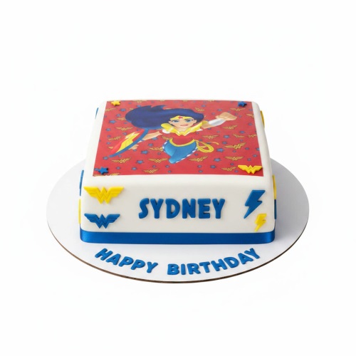 Square white fondant cake with Wonder Woman edible image, blue ribbon, and 'W' logos.
