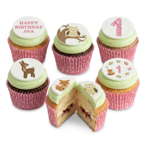 Woodland animal themed cupcakes with fox, deer, owl, and leaf toppers, green frosting, and pink polka dot cases.