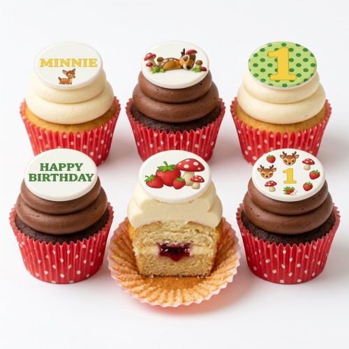 Woodland animal themed cupcakes with deer, mushroom, and strawberry toppers, some with custom age 1 and "Happy Birthday".