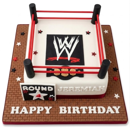 White wrestling ring cake with black posts, red ropes, WWE logo, championship belt, and brick-patterned board.