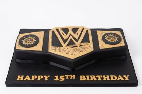 Black and gold WWE Championship Belt shaped birthday cake with 'Happy Birthday' message.