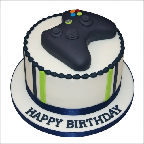 Round white birthday cake with edible Xbox controller, dark blue and green stripes.