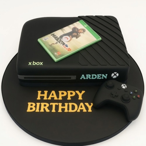 Black Xbox console shaped birthday cake with controller and game disc.