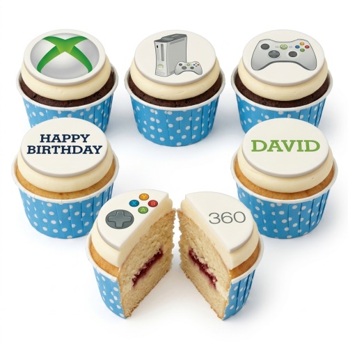 Six Xbox themed birthday cupcakes with console, controller, and logo toppers, one cut to show jam filling.