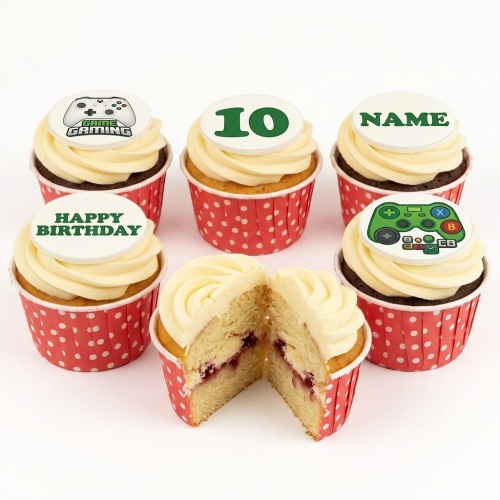Six cupcakes with white frosting and red polka dot wrappers. Toppers show game controllers, 'GAME GAMING', 'HAPPY BIRTHDAY', and a custom age topper. One cupcake is cut open showing jam filling.