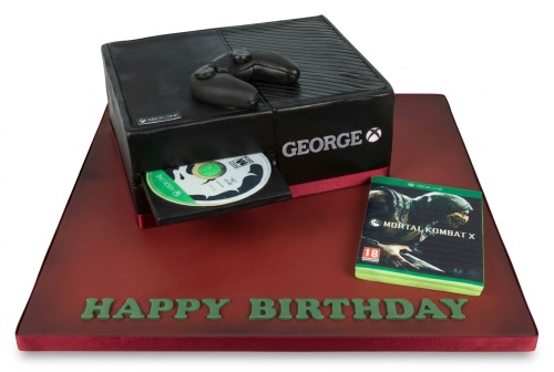 3D sculpted Xbox One console cake with controller, game disc, and game case on a red board with 'Happy Birthday' text.
