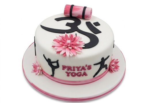 White round cake with black Om symbol, pink yoga mat, pink flowers, and black yoga pose silhouettes.