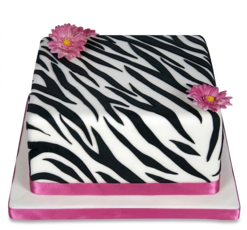 Square zebra print birthday cake with pink flowers and ribbon.